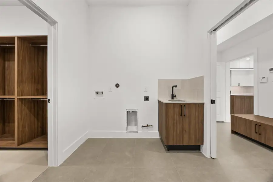 Spacious laundry room with utility sink, dual access to the primary closet and mud room.