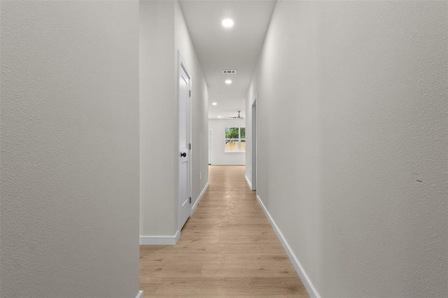 Hallway featuring light wood-finish flooring, recessed lighting, and white baseboards