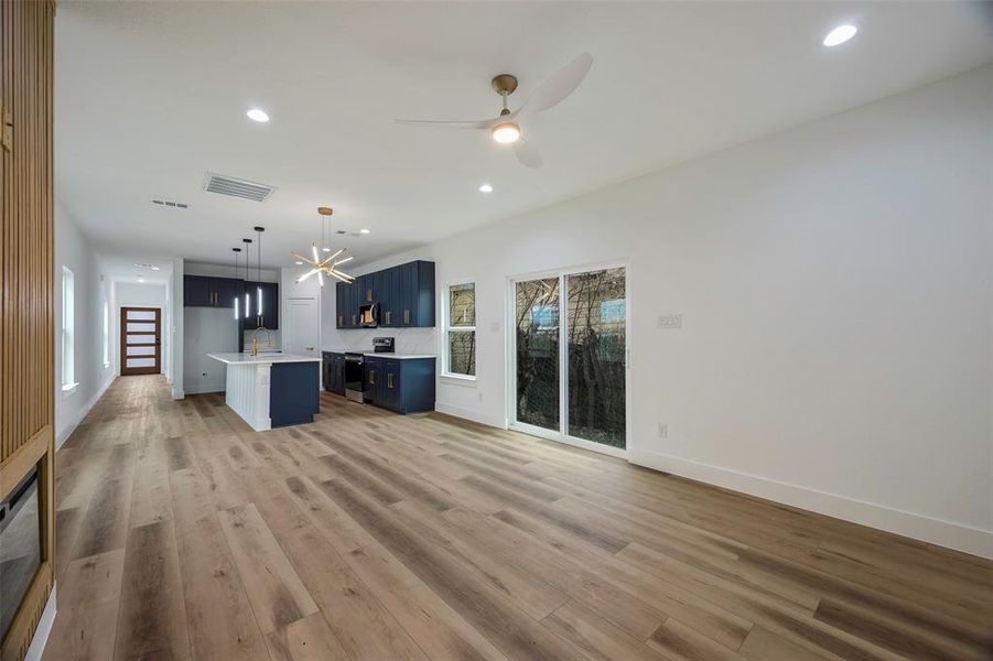 Unfurnished living room with ceiling fan, wood-type flooring, and sink