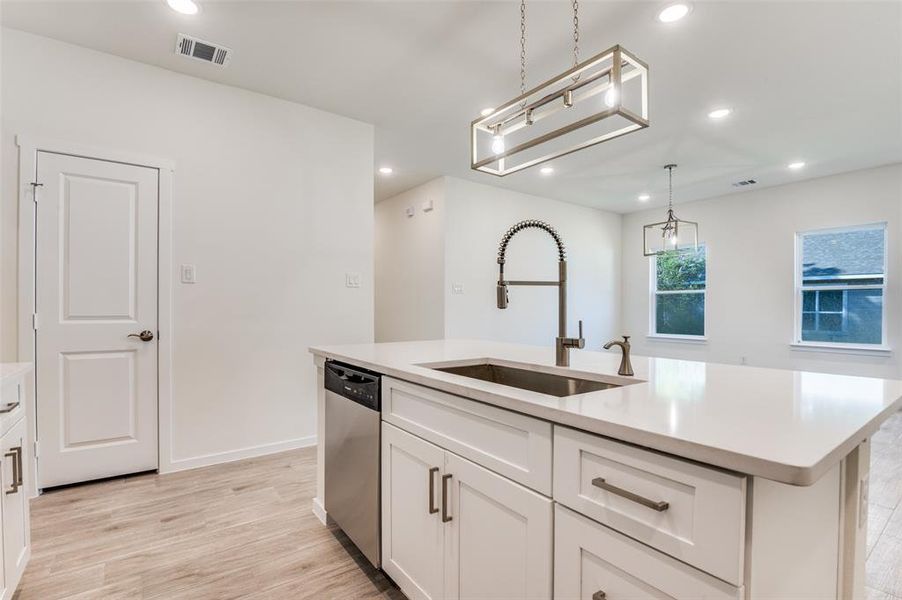 Kitchen featuring an island with sink, recessed lighting, white cabinetry, light wood-style flooring, and stainless steel dishwasher