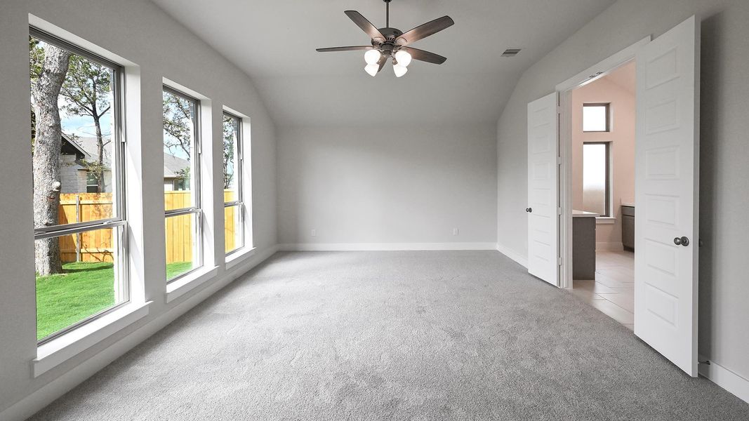 Unfurnished bedroom with lofted ceiling, light colored carpet, and a ceiling fan Unfurnished bedroom with lofted ceiling, light colored carpet, and a ceiling fan