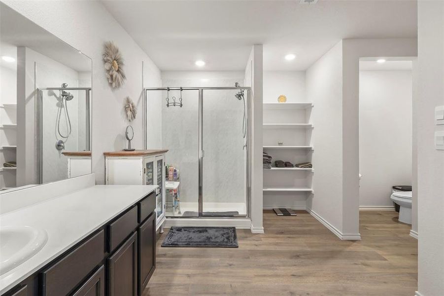 Bathroom featuring a walk in closet, light wood-style flooring, vanity, a stall shower, and recessed lighting