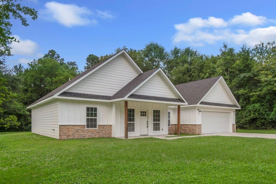 This photo shows a charming single-story home with a modern design. It features a gabled roof, a combination of white siding and stone accents, and a spacious two-car garage. The house is set on a large, lush green lawn with a backdrop of mature trees, providing a serene, private setting. This photo shows a charming single-story home with a modern design. It features a gabled roof, a combination of white siding and stone accents, and a spacious two-car garage. The house is set on a large, lush green lawn with a backdrop of mature trees, providing a serene, private setting.