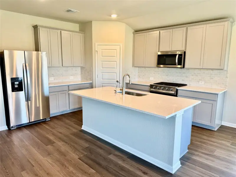 Kitchen with stainless steel appliances, dark wood-type flooring, an island with sink, backsplash, and recessed lighting Kitchen with stainless steel appliances, dark wood-type flooring, an island with sink, backsplash, and recessed lighting