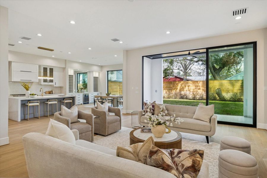 A sweeping wall of sliding glass doors brings in abundant light and creates a fluid connection to the outdoors, while the oak flooring extends into the kitchen for a cohesive, open-concept design. A sweeping wall of sliding glass doors brings in abundant light and creates a fluid connection to the outdoors, while the oak flooring extends into the kitchen for a cohesive, open-concept design.