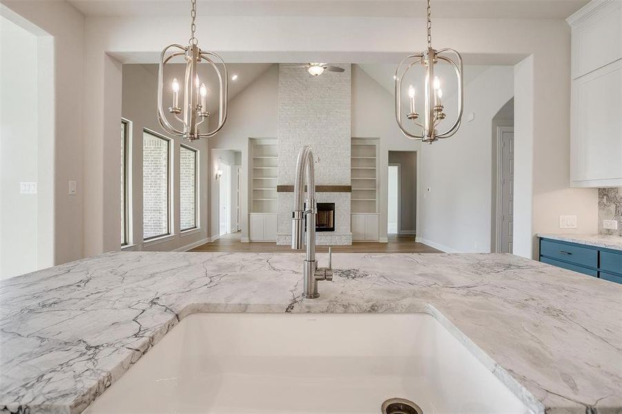 Kitchen with sink, built in features, light hardwood / wood-style floors, decorative light fixtures, and a fireplace