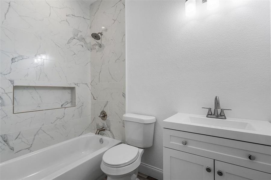 Full bathroom with vanity, bathing tub / shower combination, and a textured wall