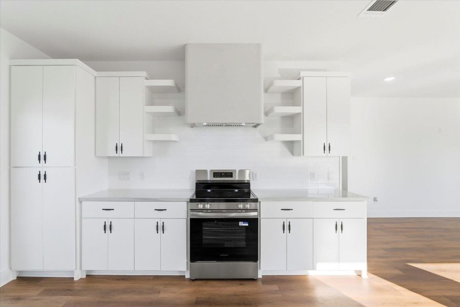 The modern kitchen features a custom stucco vent hood surrounded by exposed shelving and white subway tile backsplash.
