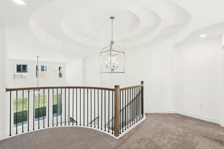 Corridor with a tray ceiling, recessed lighting, an upstairs landing, carpet, and a chandelier