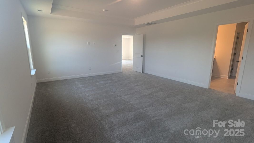 Spacious Primary Suite features plenty of light, wall space and a tray ceiling-Representative Photo