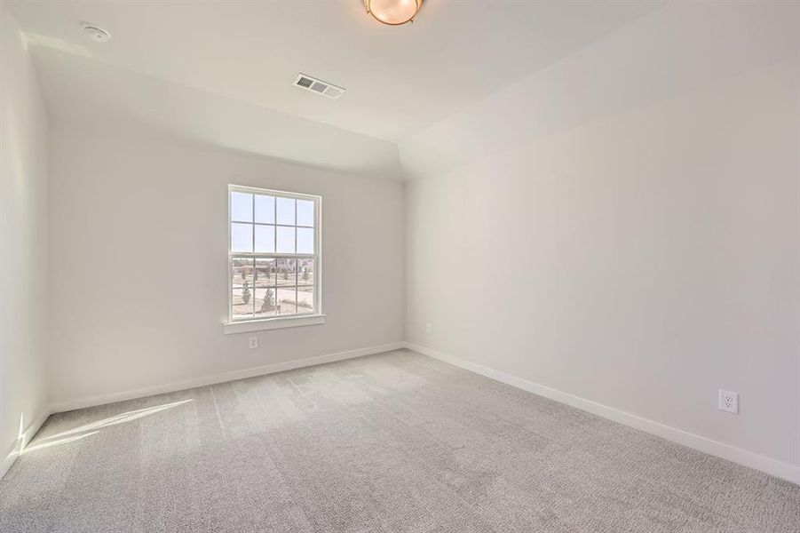 Empty room with light carpet and lofted ceiling