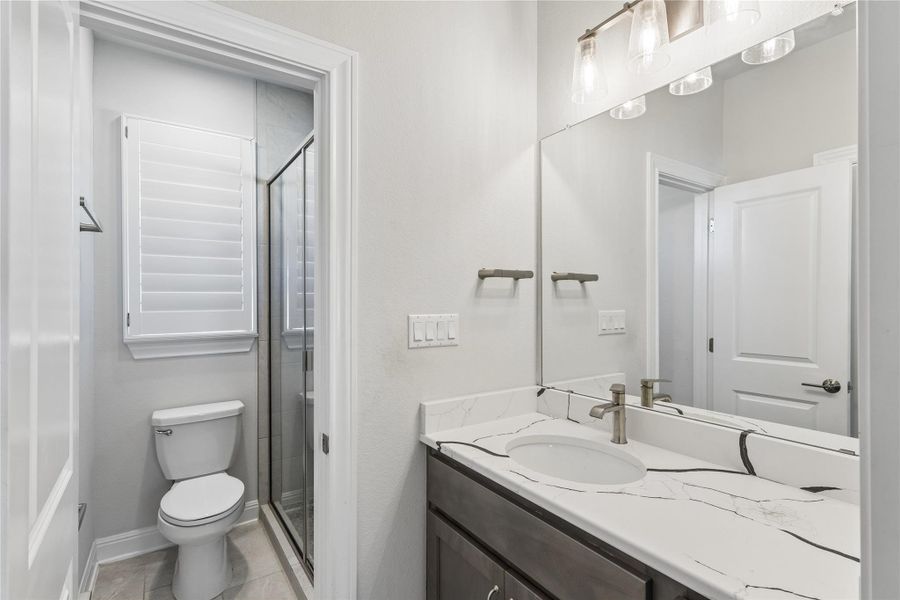 A well-appointed bathroom features a single vanity, a walk-in shower, and a private water closet.