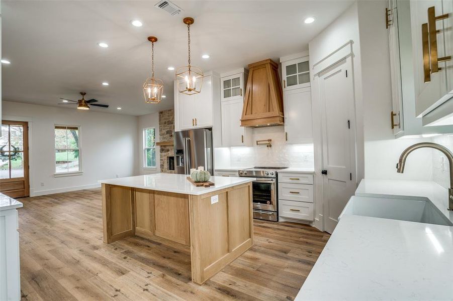 Kitchen with white cabinetry, sink, stainless steel appliances, light hardwood / wood-style flooring, and a kitchen island