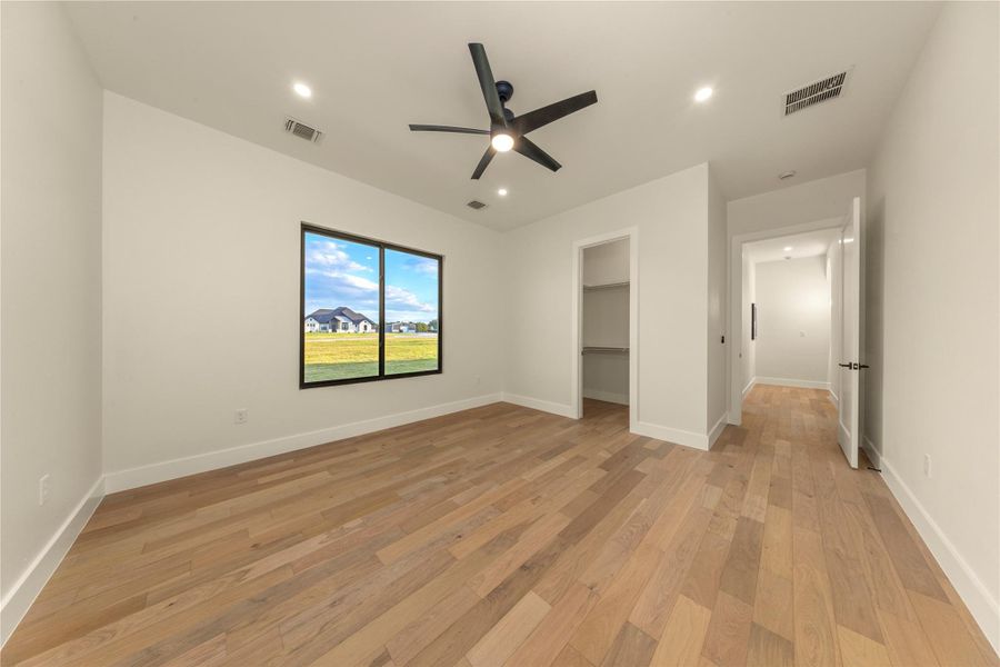 Unfurnished bedroom with a spacious closet, light wood-type flooring, a ceiling fan, and recessed lighting