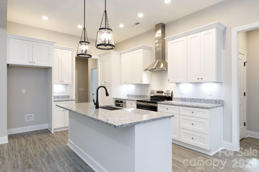 Hall to the laundry and 1/2 bath along with a hall to the primary bedroom are located off the kitchen. Hall to the laundry and 1/2 bath along with a hall to the primary bedroom are located off the kitchen.