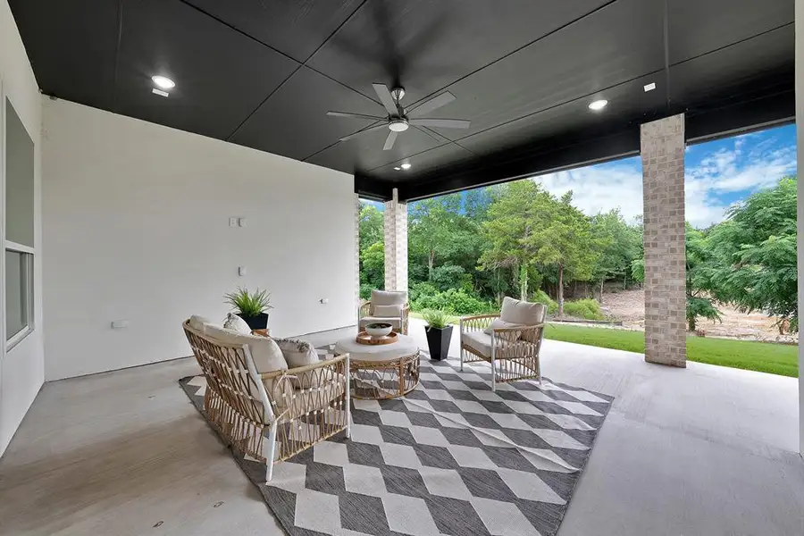 Expansive covered patio featuring a dark wood-finish ceiling, recessed lighting, and a ceiling fan