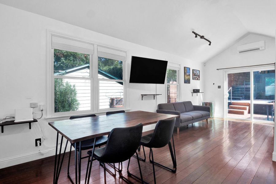 Dining room featuring a wall mounted air conditioner, lofted ceiling, dark wood-style floors, plenty of natural light, and rail lighting
