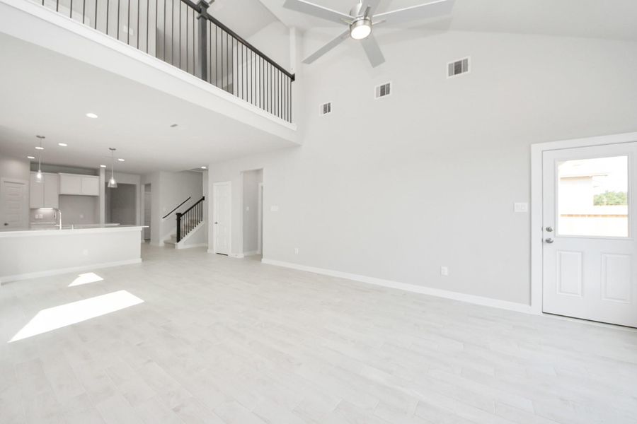 Gather your loved ones and guests in the welcoming living room! Enjoy the spaciousness created by lofty high ceilings, complemented by the glow of recessed lighting and the gentle breeze from a stylish ceiling fan. Sample photo of completed plan. As-built color and selections may vary.