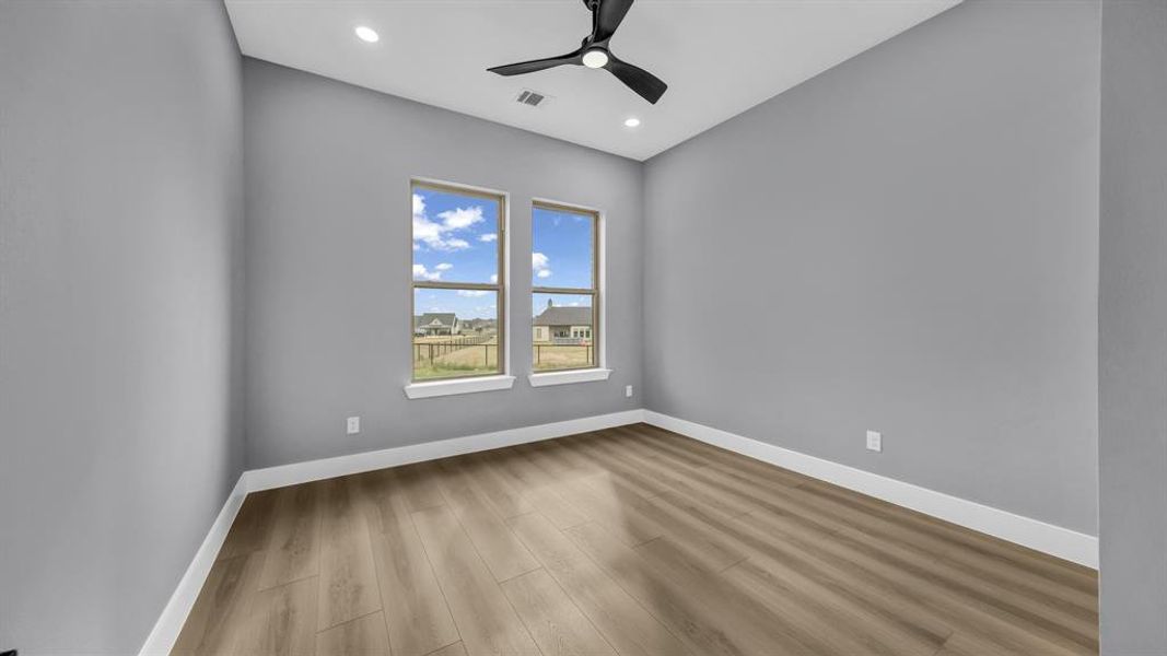 Spare room with wood finished floors, a ceiling fan, and recessed lighting