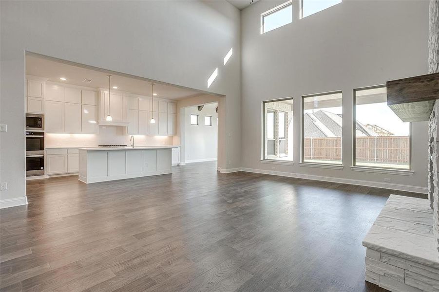 Unfurnished living room with a towering ceiling, dark wood-type flooring, and sink