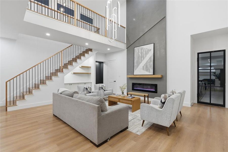 Double-height living space featuring wood-finish flooring and a contemporary linear fireplace Double-height living space featuring wood-finish flooring and a contemporary linear fireplace