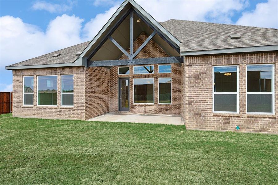 Rear view of house with a patio, brick siding, and a shingled roof