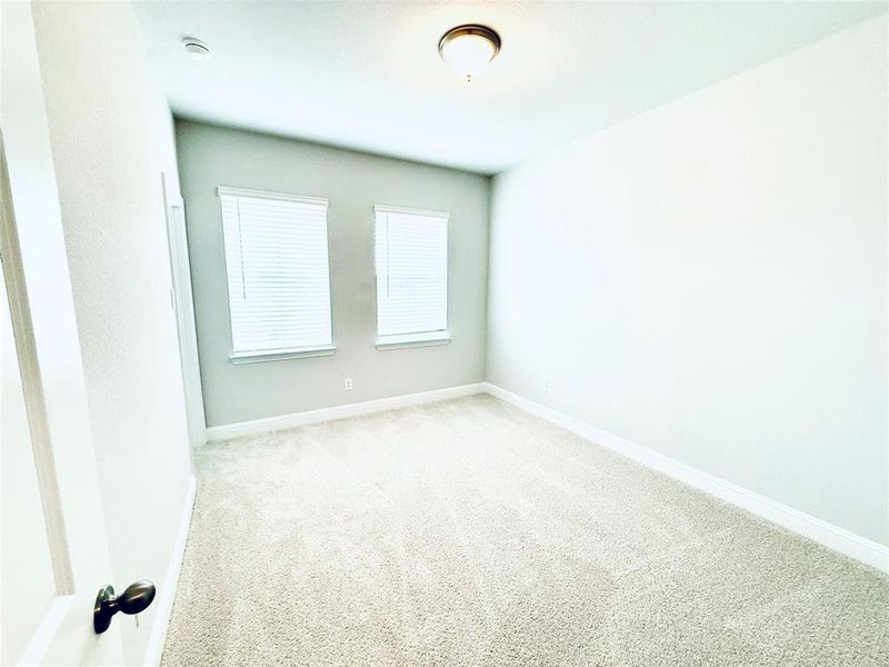 Neutral-toned wall finishes, light-colored carpeting, two windows with blinds, and ceiling-mounted lighting fixture