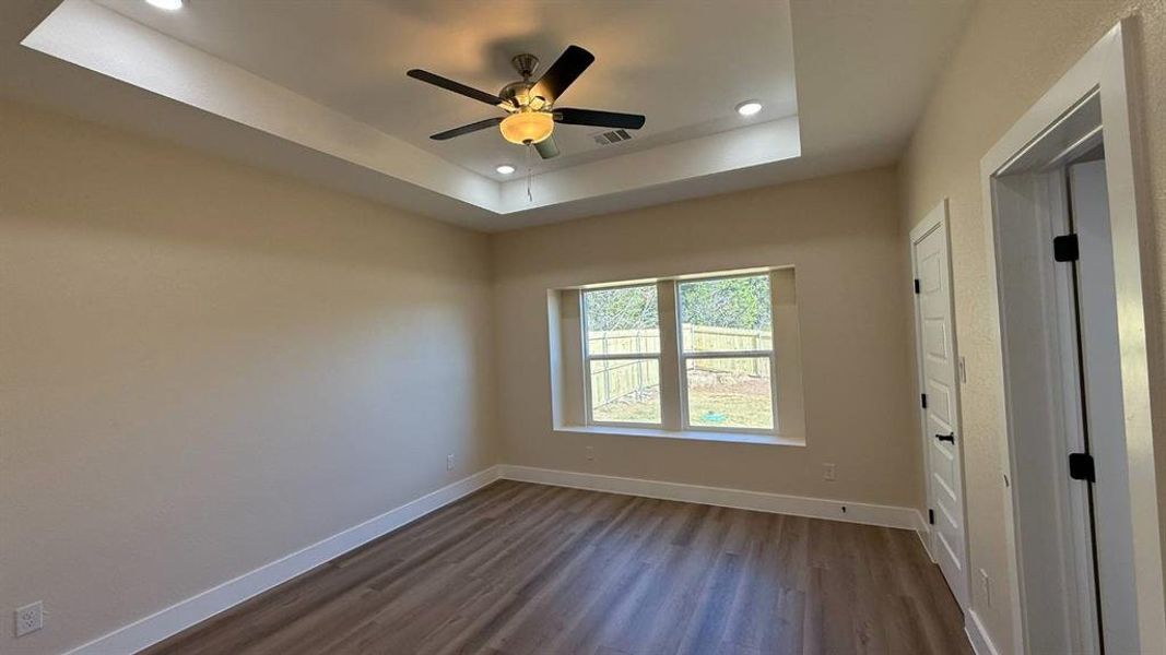 Empty room featuring dark wood finished floors, recessed lighting, a tray ceiling, and a ceiling fan