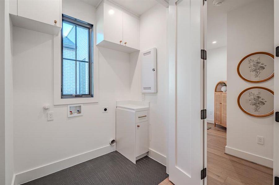 Washroom featuring electric dryer hookup, hookup for a washing machine, and cabinet space Washroom featuring electric dryer hookup, hookup for a washing machine, and cabinet space