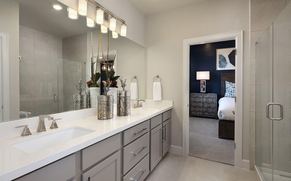 Ensuite bathroom with a shower stall, double vanity, light tile patterned floors, and light colored carpet Ensuite bathroom with a shower stall, double vanity, light tile patterned floors, and light colored carpet