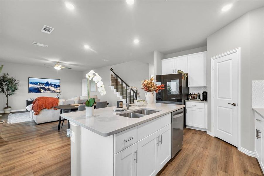 Kitchen featuring white cabinets, a kitchen island with sink, dishwasher, and sink