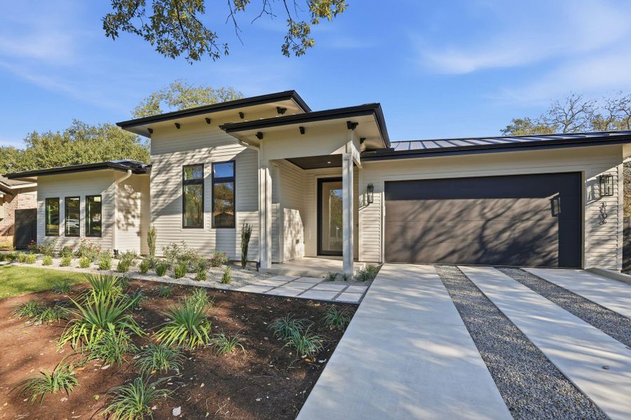 View of front of home featuring a standing seam roof, an attached garage, a metal roof, and driveway