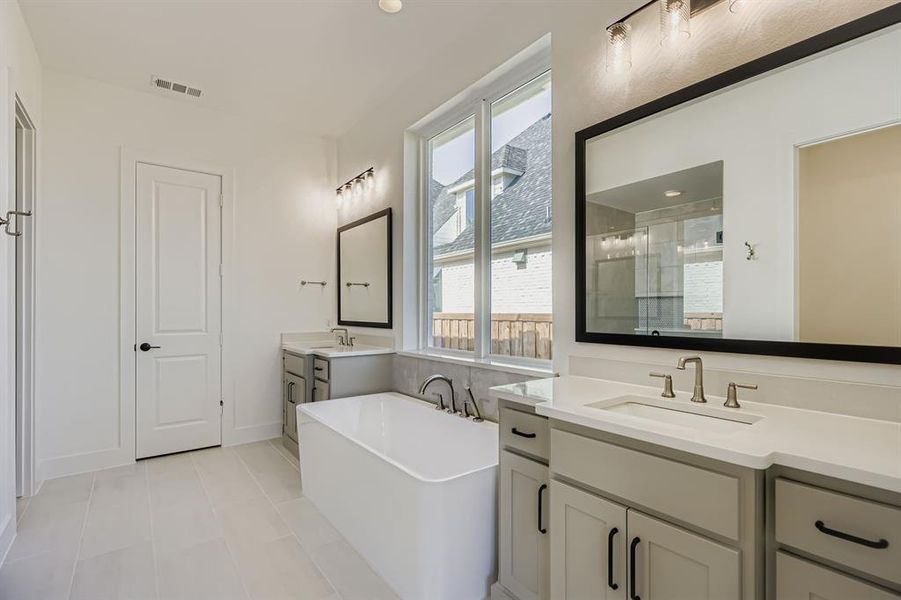 Full bathroom featuring a stall shower, two vanities, a soaking tub, and tile patterned flooring