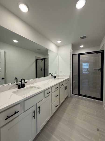 Bathroom with double vanity, a shower stall, and recessed lighting