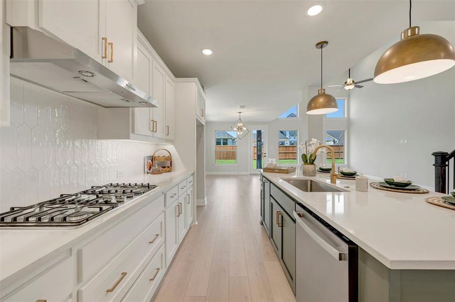 Modern kitchen featuring white cabinetry, a gas cooktop with a stainless steel range hood, and a white elongated hexagonal tile backsplash