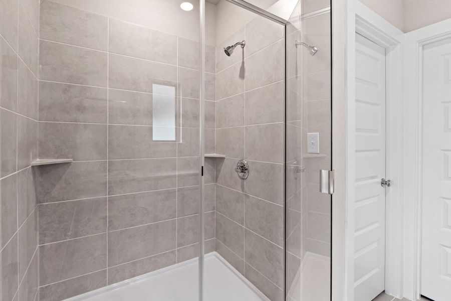 A well-appointed, naturally illuminated shower with sleek glass enclosure offers a refreshing bathing experience.