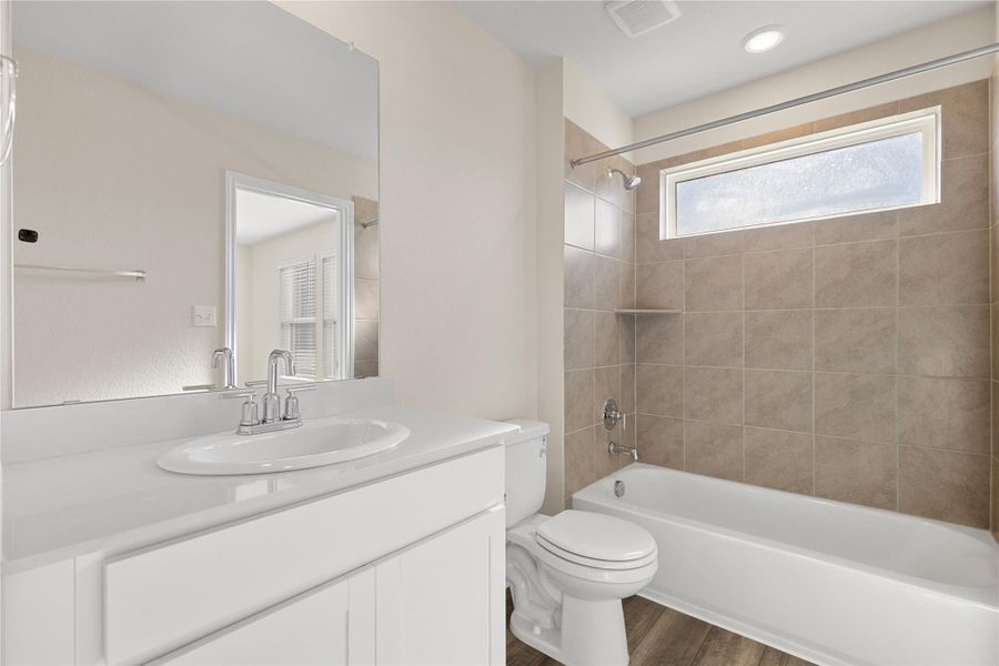 Bathroom with bathing tub / shower combination, vanity, and dark wood-style floors Bathroom with bathing tub / shower combination, vanity, and dark wood-style floors