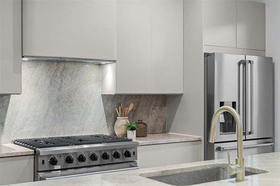 Kitchen featuring appliances with stainless steel finishes, decorative backsplash, light stone countertops, and modern cabinets