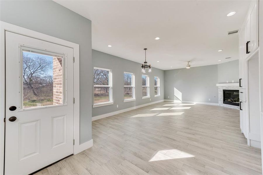 Foyer entrance featuring light hardwood / wood-style flooring, ceiling fan with notable chandelier, and a wealth of natural light