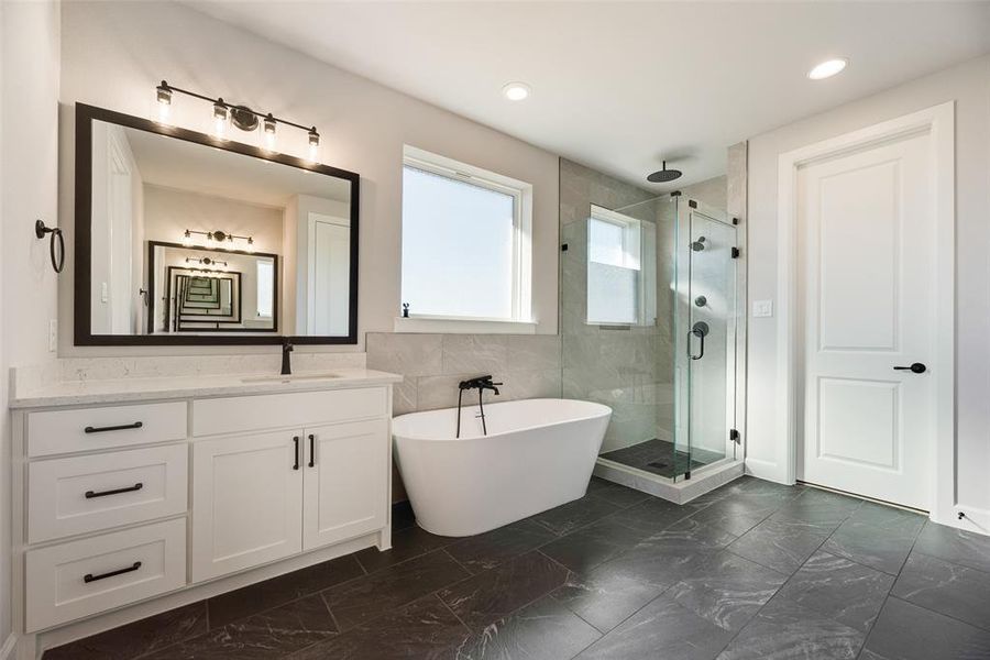 Full bathroom with a soaking tub, a stall shower, vanity, tile walls, and dark marble finish floors Full bathroom with a soaking tub, a stall shower, vanity, tile walls, and dark marble finish floors