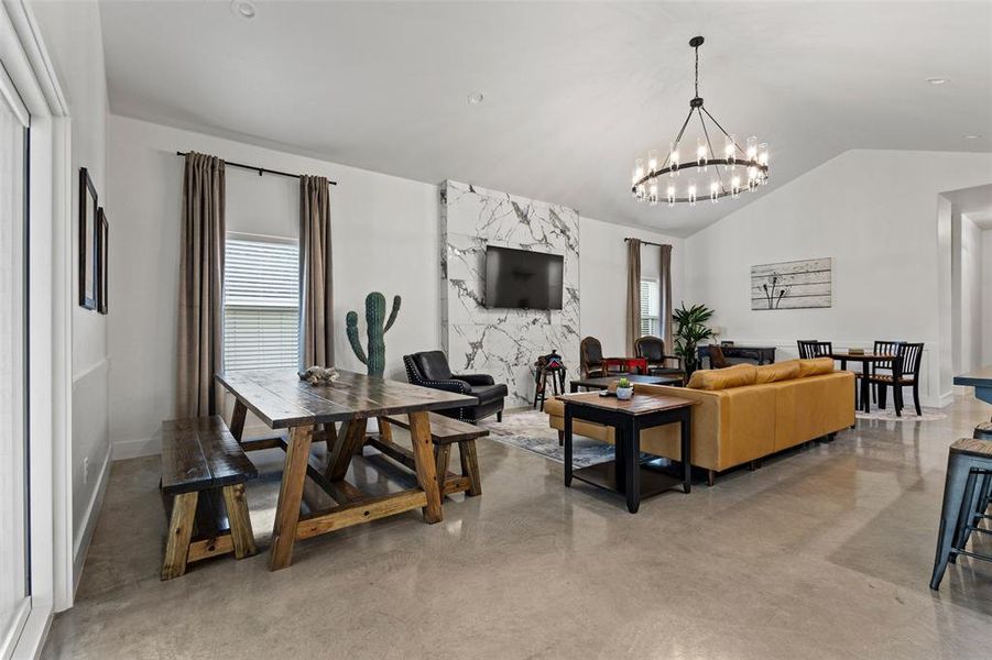 Living area with concrete floors, hanging lights, lofted ceiling, and healthy amount of natural light