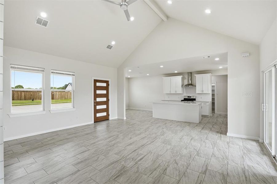 Open-concept interior featuring light gray wood-finish tile flooring, vaulted ceilings, and recessed lighting