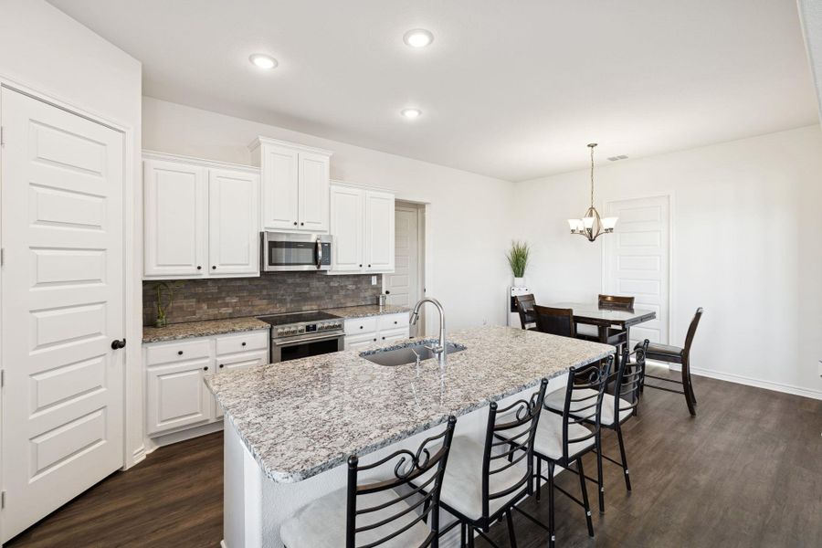 Kitchen with backsplash, a kitchen breakfast bar, appliances with stainless steel finishes, white cabinets, and recessed lighting Kitchen with backsplash, a kitchen breakfast bar, appliances with stainless steel finishes, white cabinets, and recessed lighting
