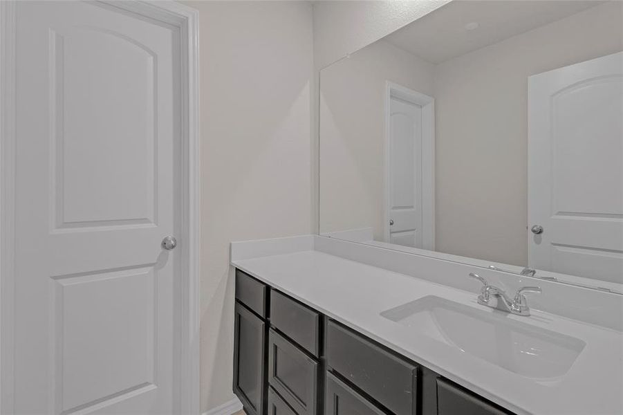 The photo shows a clean and modern bathroom with a large vanity and a double sink, featuring ample under-sink storage. Two doors suggest convenient access and potential for privacy or additional rooms. The neutral color palette provides a versatile backdrop for personalization.