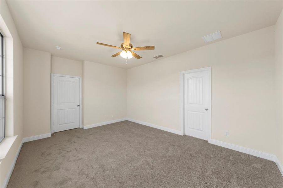 Empty room with ceiling fan and light colored carpet