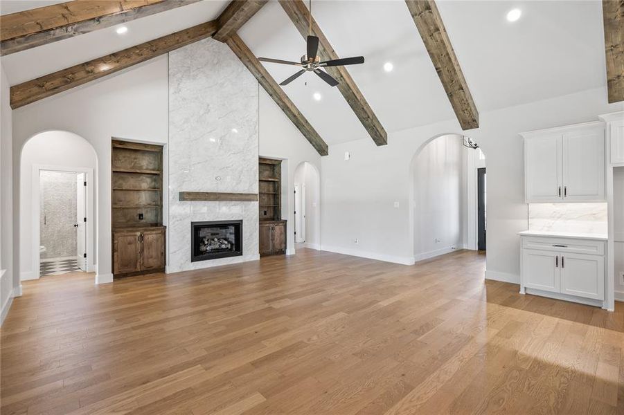 Unfurnished living room featuring arched walkways, ceiling fan, light wood finished floors, a fireplace, and recessed lighting