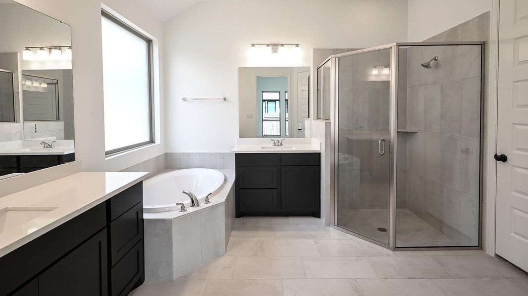 Bathroom featuring a stall shower, two vanities, a bath, and light tile patterned floors Bathroom featuring a stall shower, two vanities, a bath, and light tile patterned floors