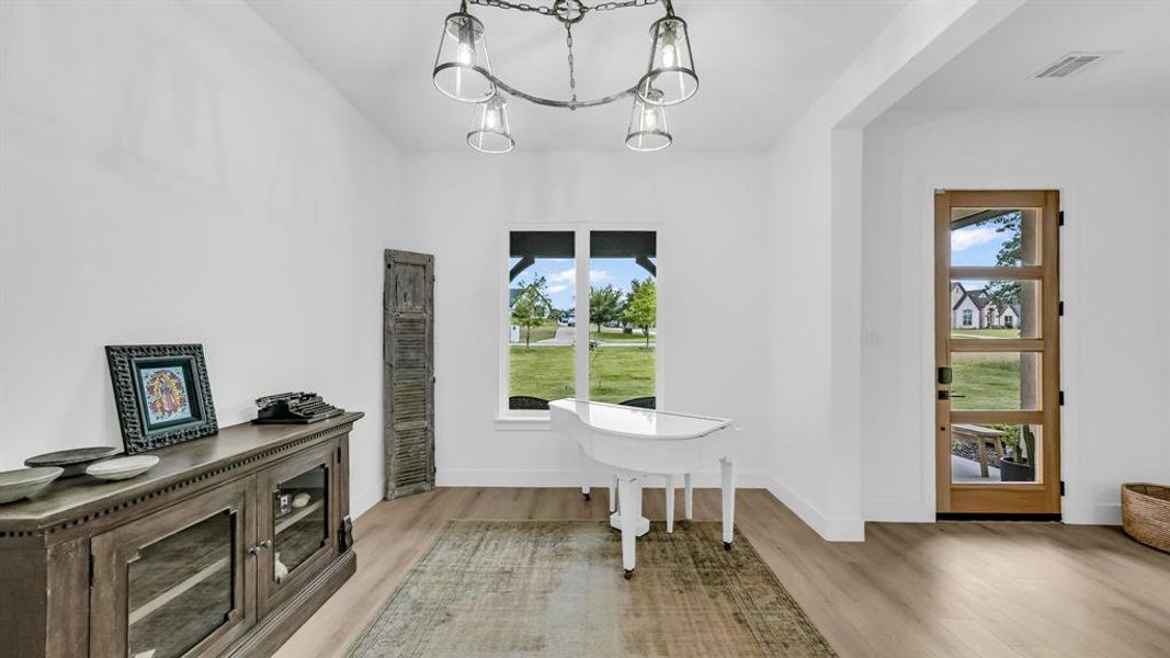 Entryway with wood finished floors, healthy amount of natural light, and a chandelier Entryway with wood finished floors, healthy amount of natural light, and a chandelier
