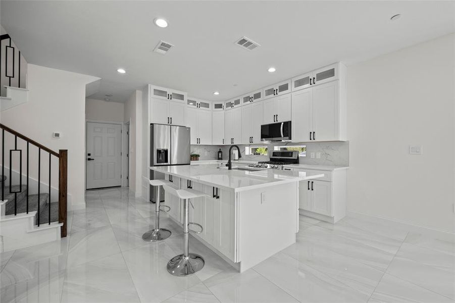 Kitchen featuring an island with sink, stainless steel appliances, a breakfast bar, and tasteful backsplash