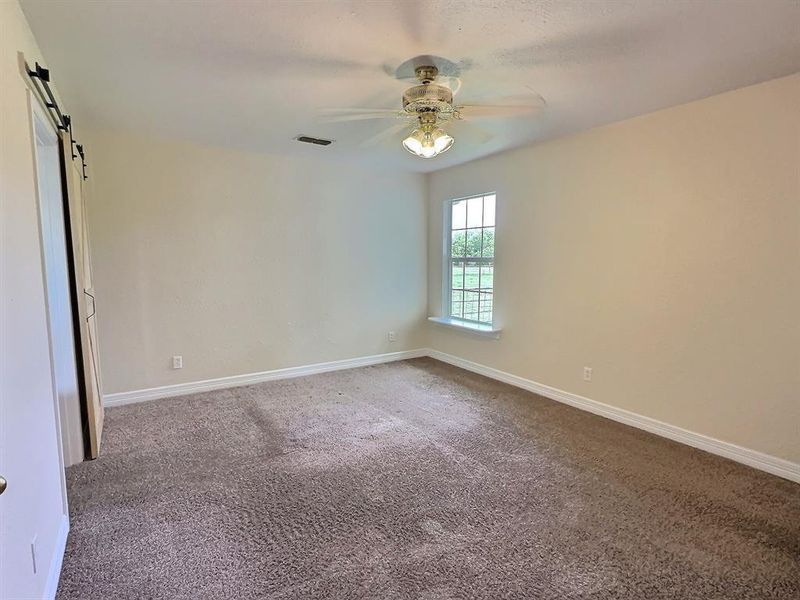 Carpeted spare room with a ceiling fan and a barn door